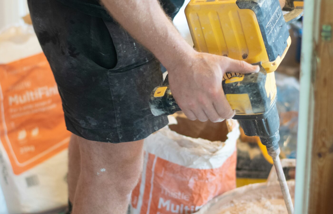 A plasterer in light-coloured work trousers smoothing a freshly skimmed wall