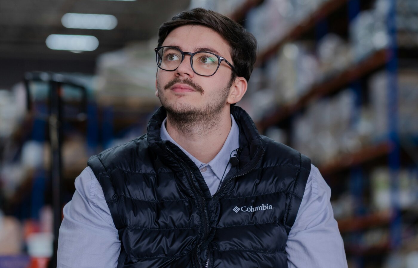 Two workers in plain navy padded gilets over grey hoodies in a timber yard on a cold autumn morning